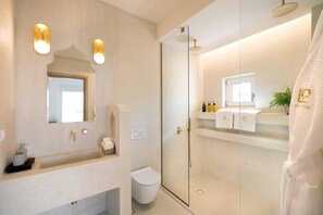 Een moderne badkamer met een glazen douche, een wastafel met spiegel en een toilet.