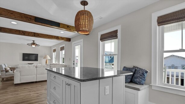 A modern kitchen with a central island, wooden beams on the ceiling, and large windows. - Ocean & Sound Views, Elevator, Close to Beach & Dining! (Wrightsville Beach)