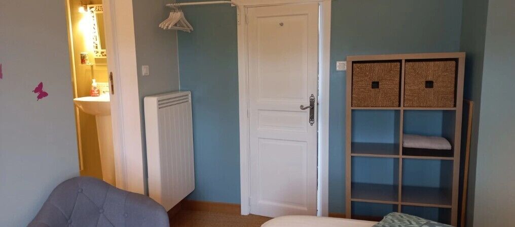 Ein Schlafzimmer mit Bett, Kleiderschrank, Heizkörper und Tür.