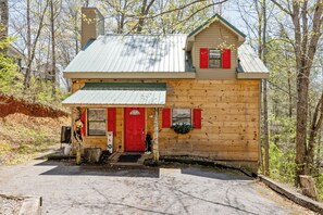 A wooden cabin with a red door, a small porch, and a metal roof. - 2BR Getaway with Hot Tub, Firepit & Outdoor TV Fun! (Gatlinburg)