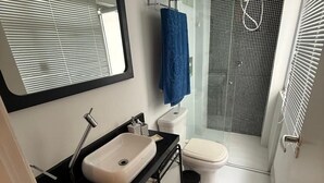 Une salle de bain moderne avec un lavabo noir, des toilettes blanches et une douche à parois de verre.