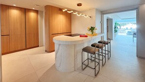 Una cocina moderna con armarios de madera, una isla de mármol y taburetes de bar.