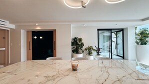 Una cocina moderna con encimera de mármol, electrodomésticos integrados y puerta de cristal que da a un comedor.