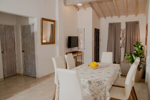 A dining area with a table set for four, a television on a stand, and a potted plant. - 2BR APARTMENT IN THE WALLED CITY (Cartagena)
