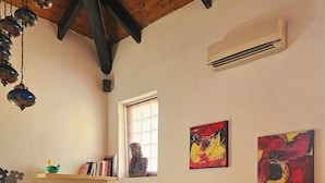 A living room with a blue sofa, a wooden ceiling, an air conditioner, and two abstract paintings. - Cozy and quiet apartment in ideal location in Reggio Cal. (Reggio Calabria)