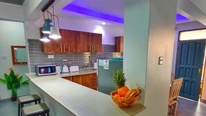 Una cocina moderna con una isla central, taburetes de bar y un frutero.