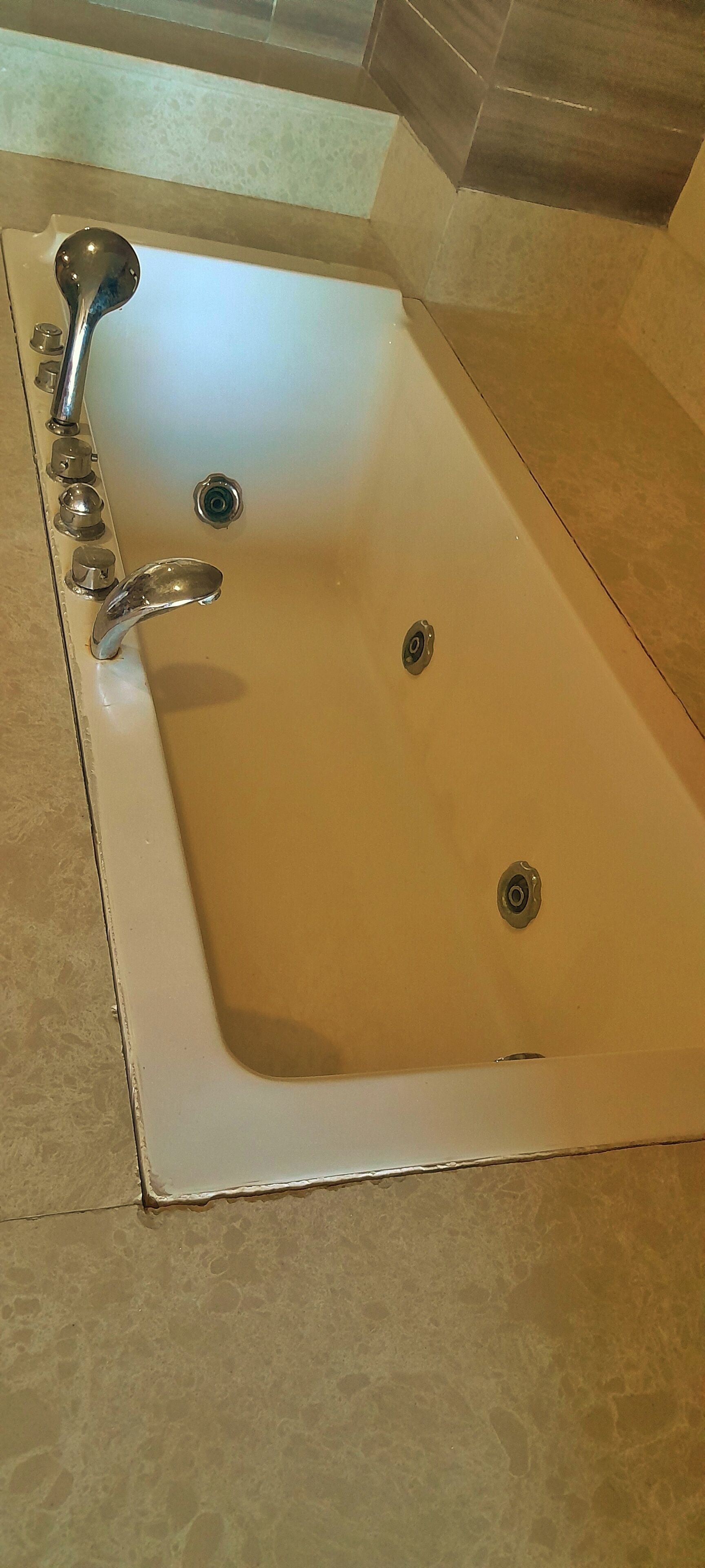 A bathroom with a white bathtub, a faucet, and a drain.