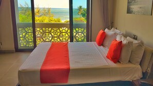 Una habitación de hotel con una cama grande, vistas al mar y un balcón con celosía.