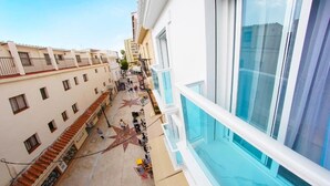 Un pasillo de hotel con un pasillo central, balcones y un ventanal grande a la derecha.