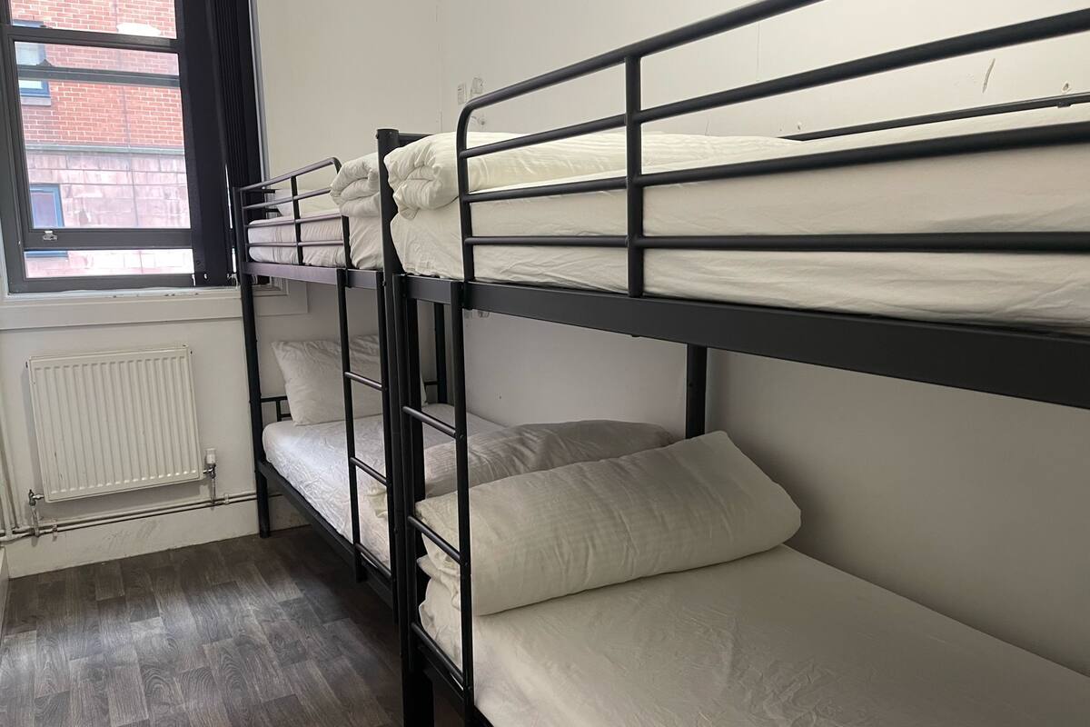 Dormitorio con literas, un radiador y una ventana.