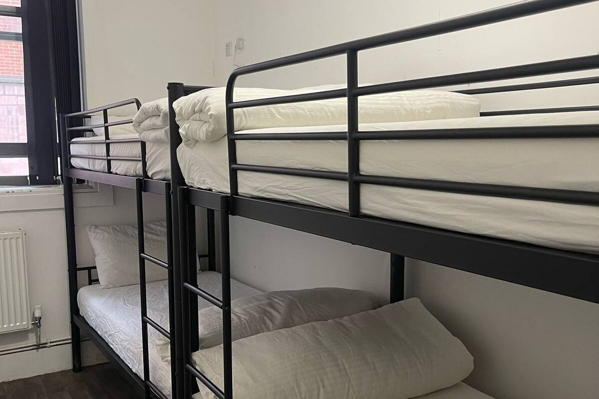 Un dormitorio con literas, un radiador y una ventana con cortinas.