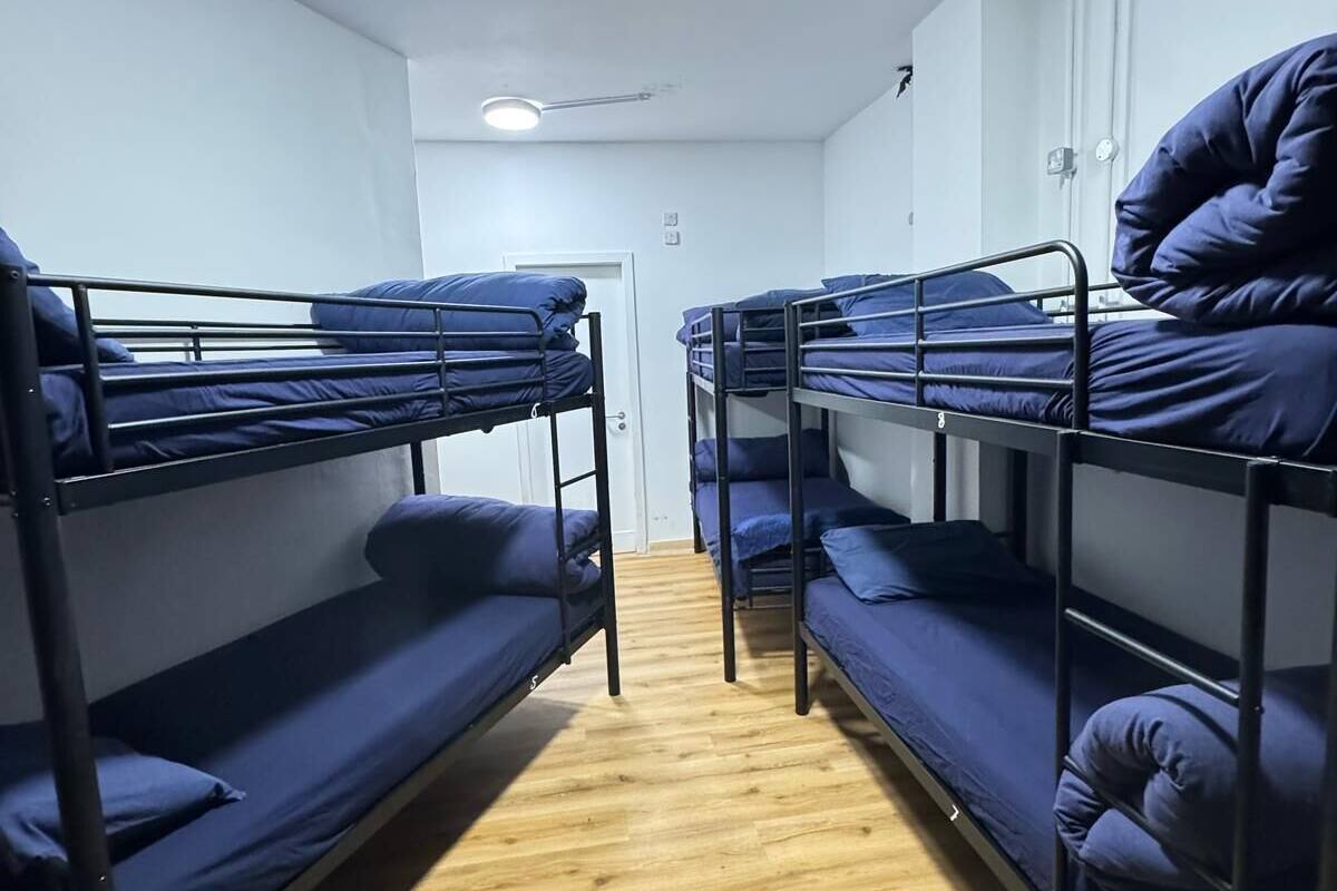Un dormitorio con literas, suelo de madera y una puerta blanca.
