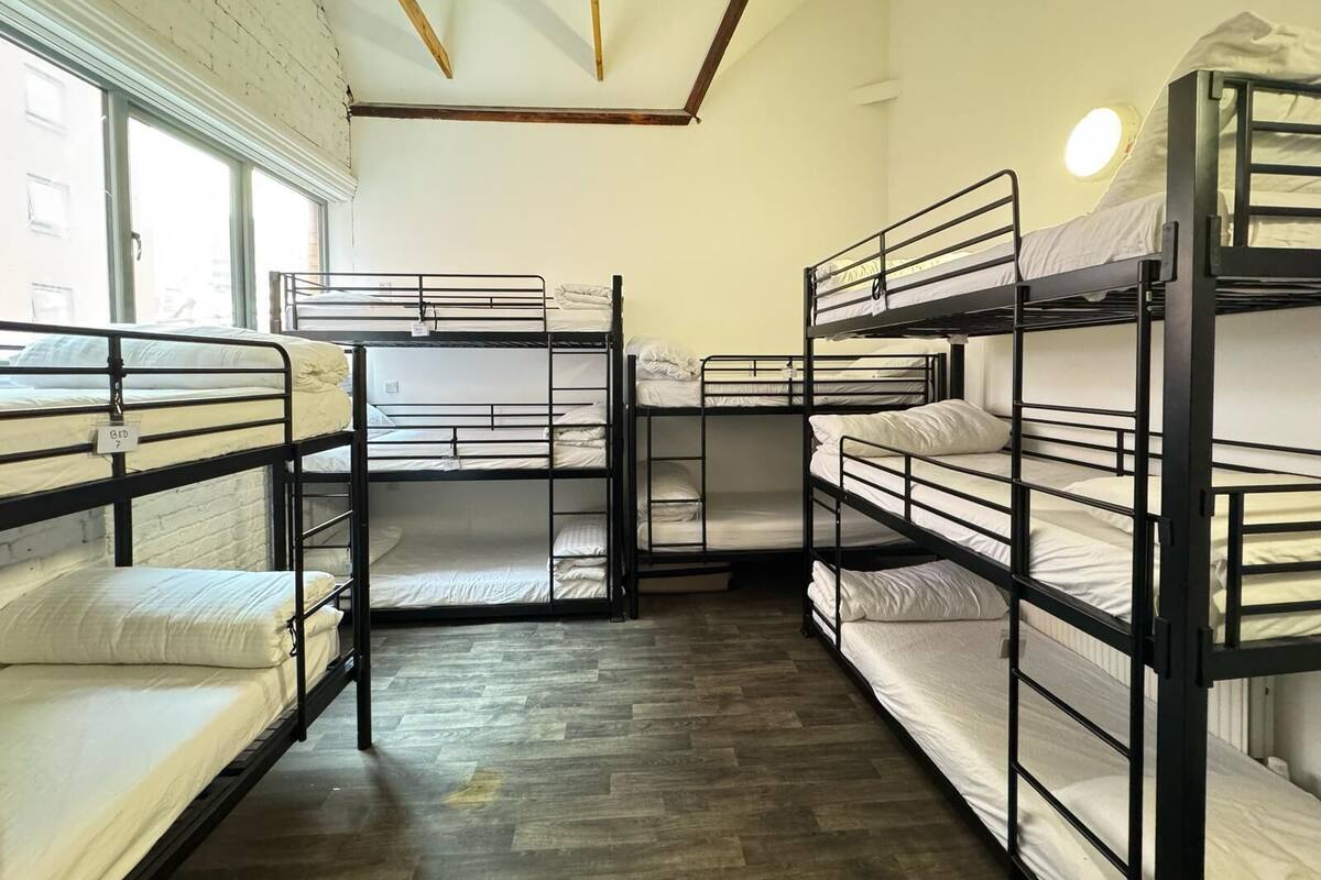 Un dormitorio con literas, vigas de madera en el techo y ventanas amplias.