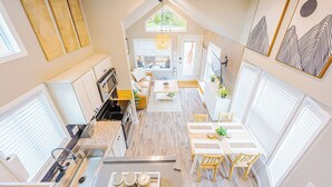 Una cocina moderna con una isla central, un comedor con mesa y sillas, y una sala de estar con sofá y mesa de centro.