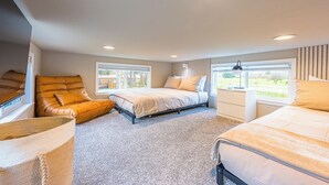 Un dormitorio con cama, sofá y sillón. Hay ventanas y una lámpara en el techo.