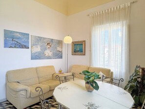 A living room with a beige sofa, a round table, and a potted plant.