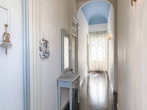 A hallway with a light blue archway, a welcome sign, a mirror, and a decorative wall hanging.