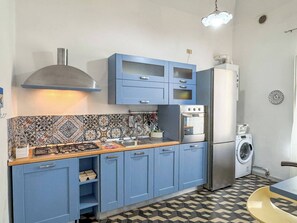 A compact kitchen with blue cabinets, a gas stove, a built-in oven, and a washing machine.
