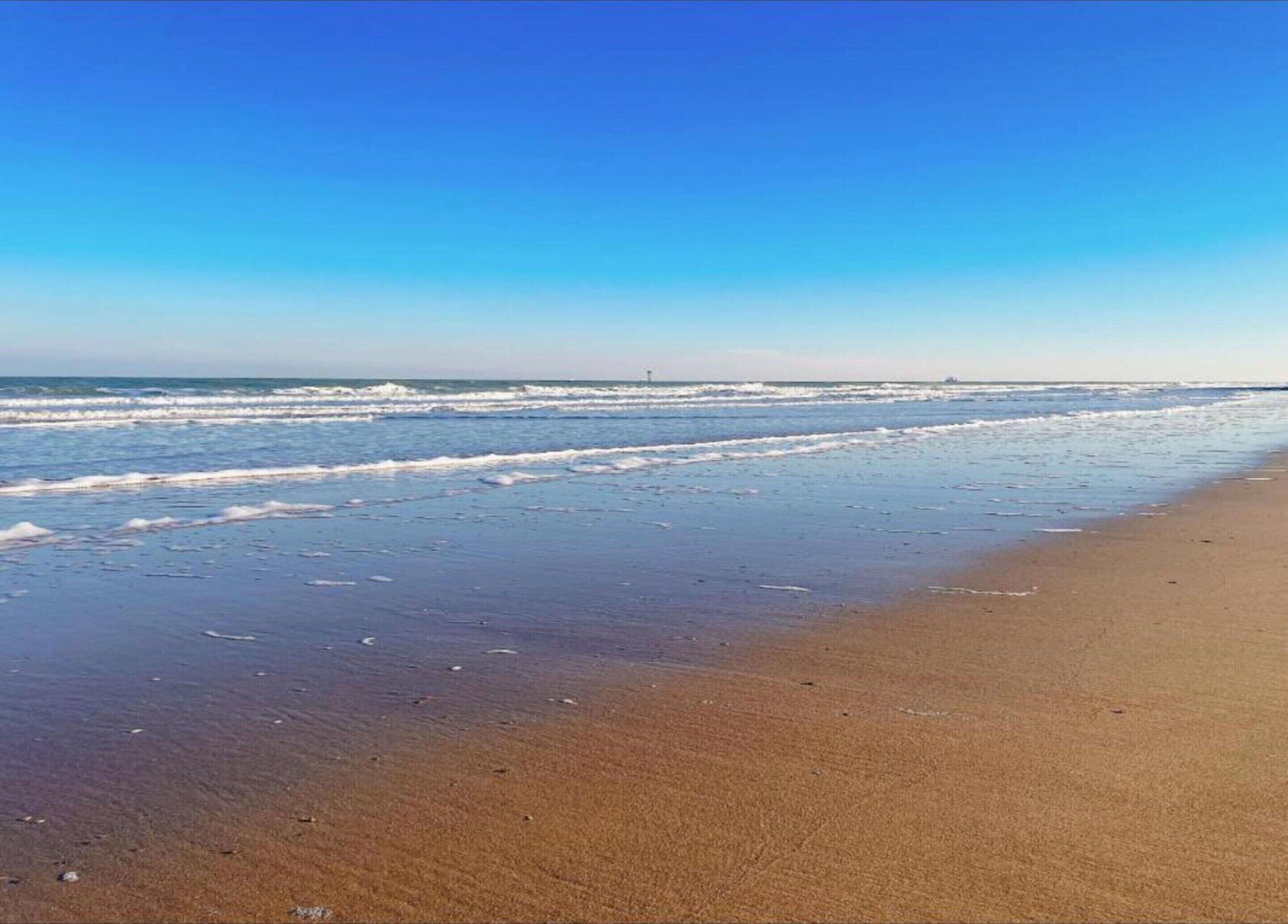 A beach with a clear sky and waves.