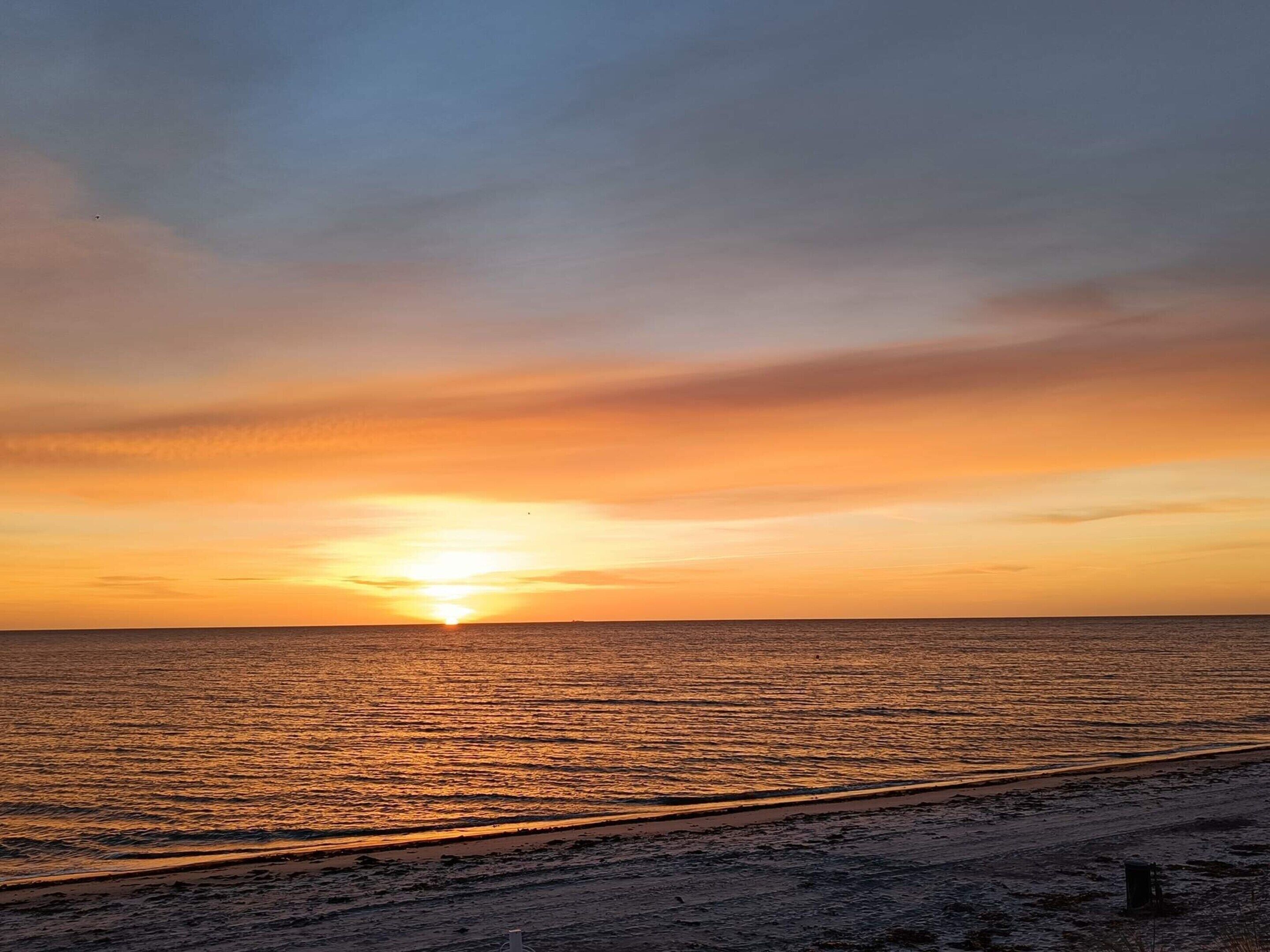 Un coucher de soleil sur une plage, avec un ciel dégagé.