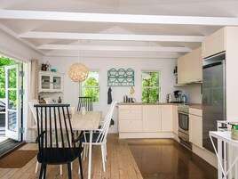Una cocina moderna con armarios blancos, un comedor con mesa y sillas, y un ventanal que proporciona luz natural.