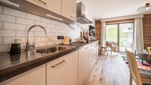 Een moderne keuken met een RVS spoelbak, witte kasten en een houten aanrecht.