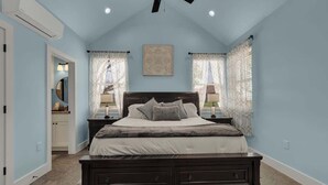 Un dormitorio con una cama de madera oscura, un ventilador de techo y dos lámparas de noche.