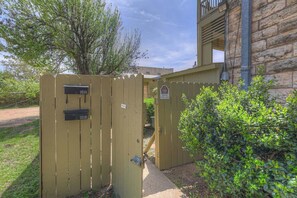 A wooden gate with a mailbox labeled '101A' and '101B' on a property with a stone building and a tree in the background. - Stay in the Heart of Fredericksburg on Main Street (Fredericksburg)