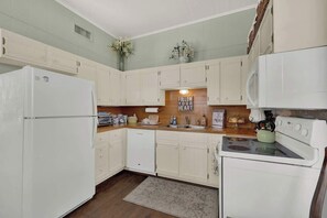 A kitchen with white cabinets, a refrigerator, a dishwasher, and a stove. - Stay in the Heart of Fredericksburg on Main Street (Fredericksburg)