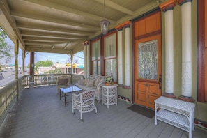 A covered porch with wicker furniture, a small table, and a bench.