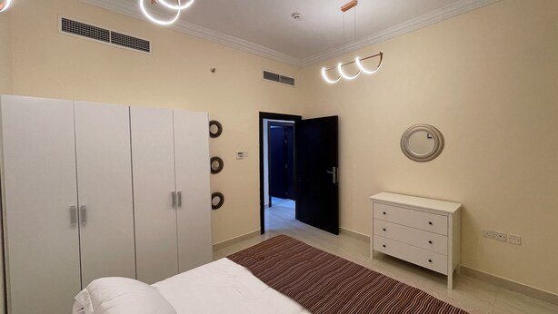 Een slaapkamer met een bed, een kledingkast, een nachtkastje en een deur naar een andere kamer.
