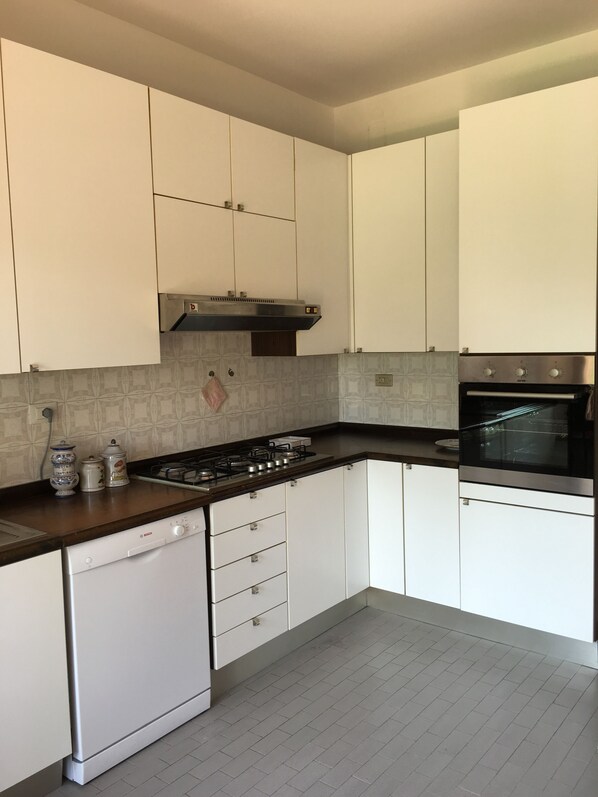 Une cuisine moderne avec des meubles blancs, un lave-vaisselle Bosch, une cuisinière à gaz et un four encastré.