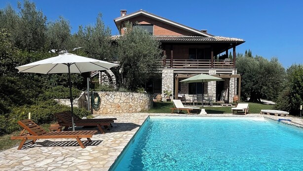 A swimming pool with lounge chairs and umbrellas, surrounded by a stone deck and a house with a balcony. - The tranquility of the Umbrian countryside a stone's throw from the center of Perugia (Umbria)