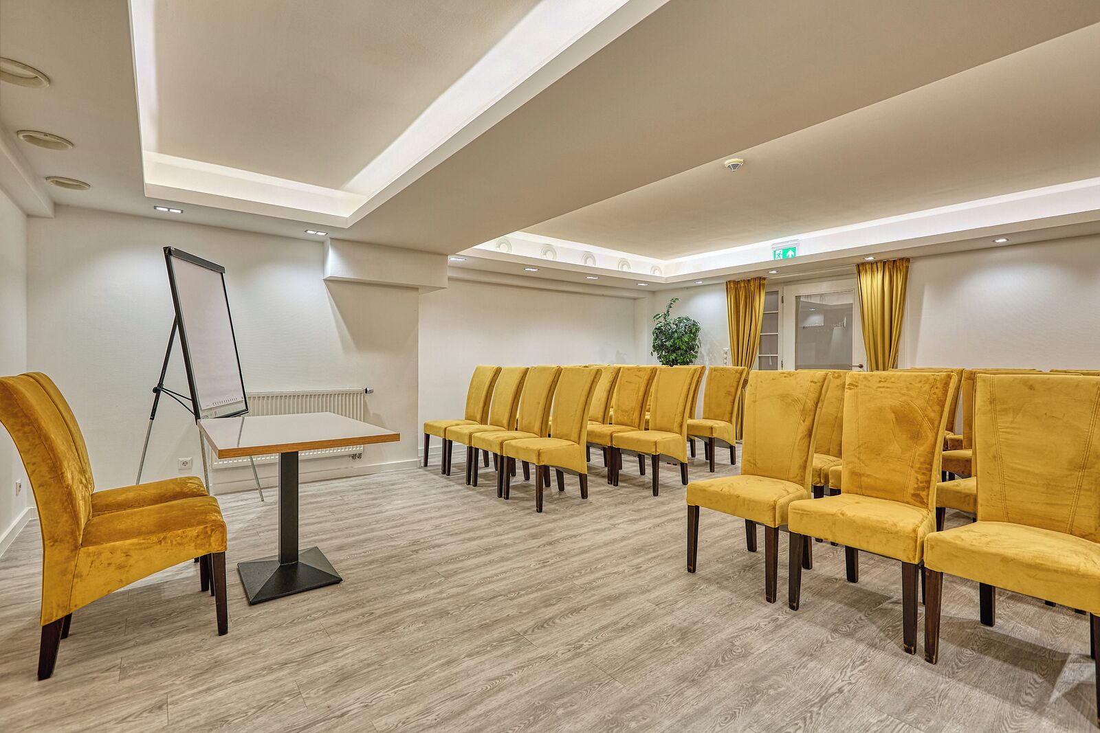 A conference room with a whiteboard, a table, and rows of yellow chairs.
