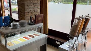 A buffet area with a stone accent wall, a coffee station, and a view of the parking lot.