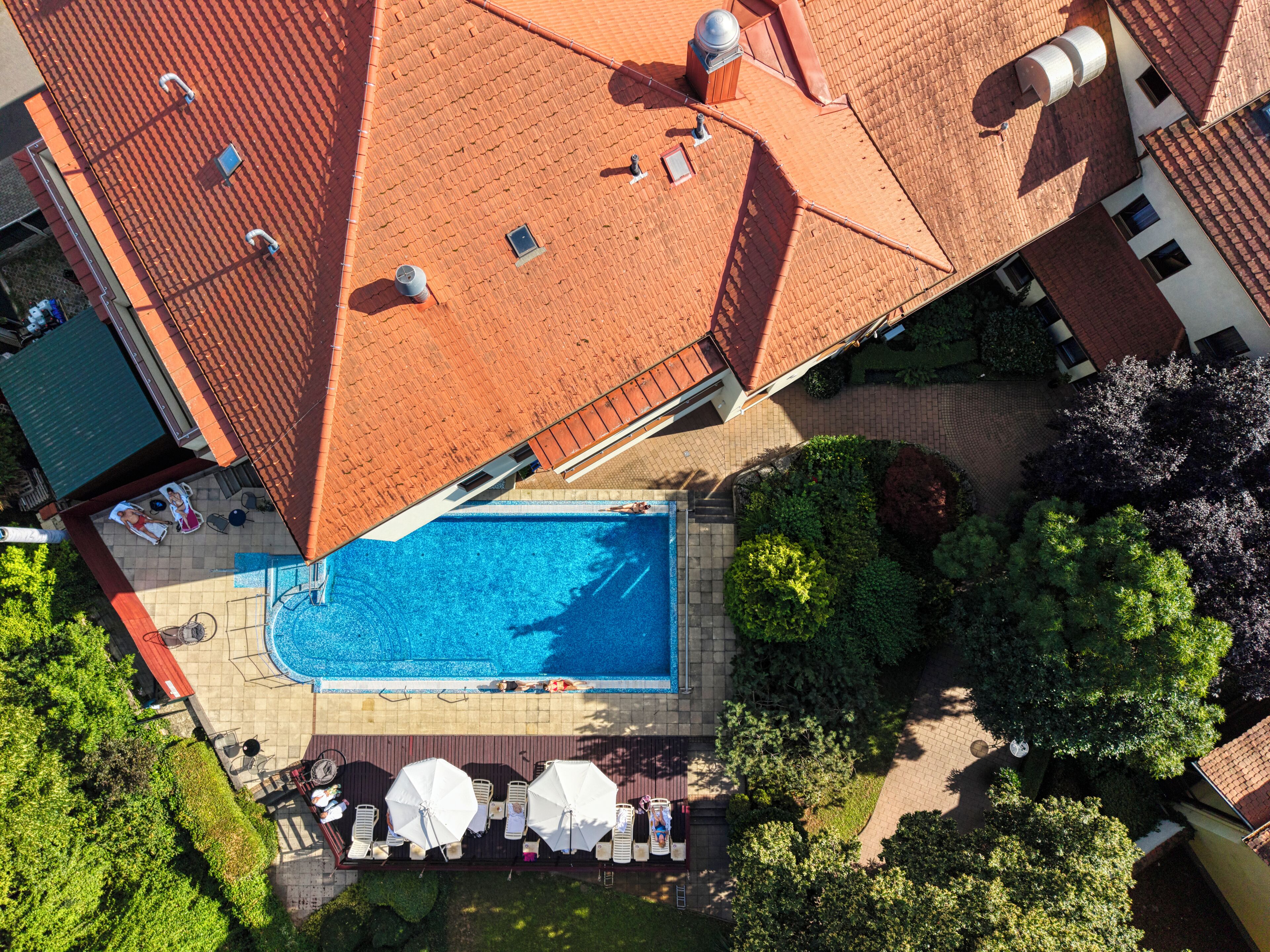 Vista aerea di una zona residenziale con piscina, lettini e ombrelloni.