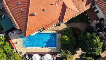 Vista aerea di una zona residenziale con piscina, lettini e ombrelloni.