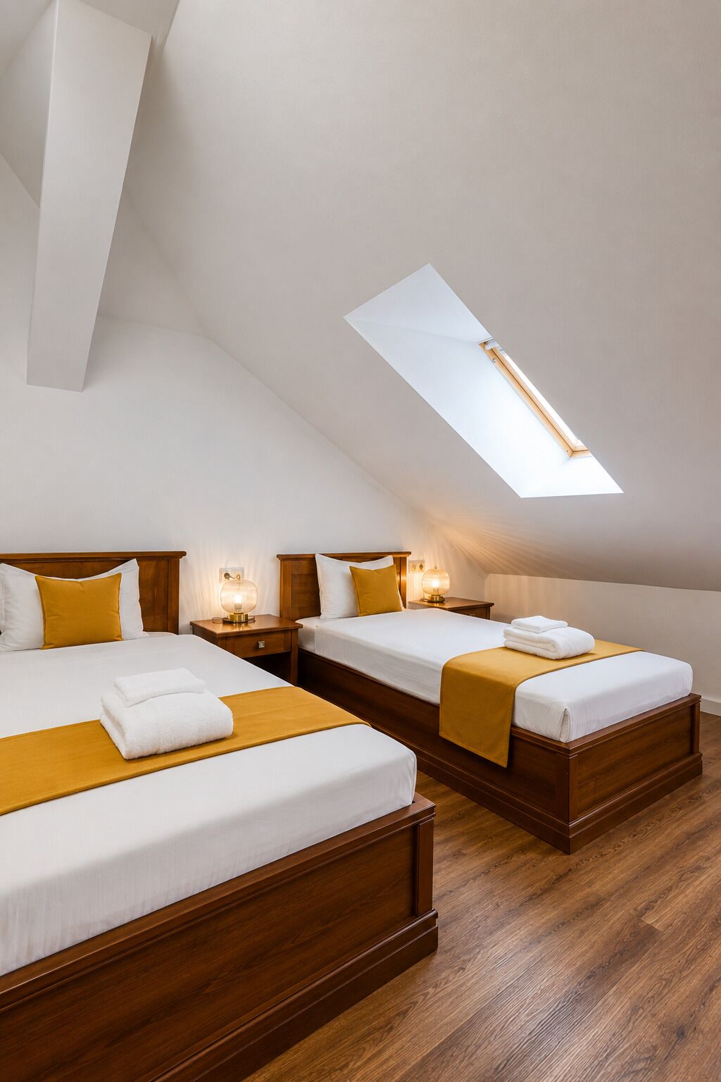 Habitación de hotel con dos camas, cabeceros de madera y un tragaluz.