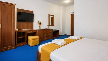 Quarto de hotel com cama, secretária, televisão de tela plana, guarda-roupa e espelho.