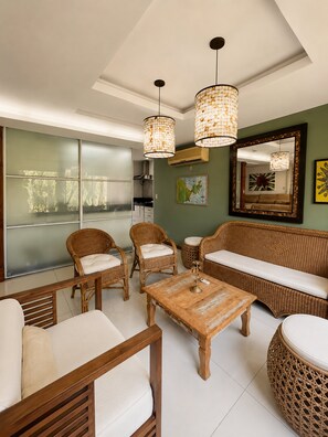 A modern living room with wicker furniture, a wooden coffee table, and pendant lighting.