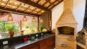 Una cocina con horno de ladrillo, armarios de madera y lámparas colgantes.