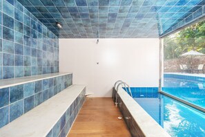 Un baño con suelo de madera, bañera blanca y pared con azulejos azules.