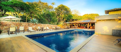 Una piscina con sillas de descanso y un muro de piedra.