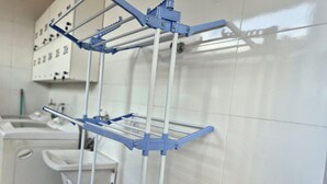 A clinical setting with a metal rack system for hanging items, a sink, and a cabinet with drawers. - Residencial Aurelio Souza (Pouso Alegre)