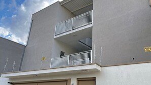 A two-story building with a grey facade, a balcony on the upper floor, and a garage door marked with the number 160. - Residencial Aurelio Souza (Pouso Alegre)
