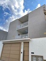 Un edificio de dos pisos con fachada gris, un balcón en el nivel superior y una puerta de garaje con el número 160.