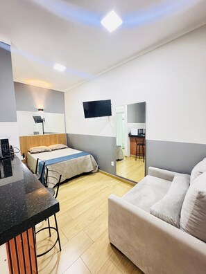 Una habitación de hotel moderna con una cama, un sofá, un escritorio y un televisor de pantalla plana montado en la pared.