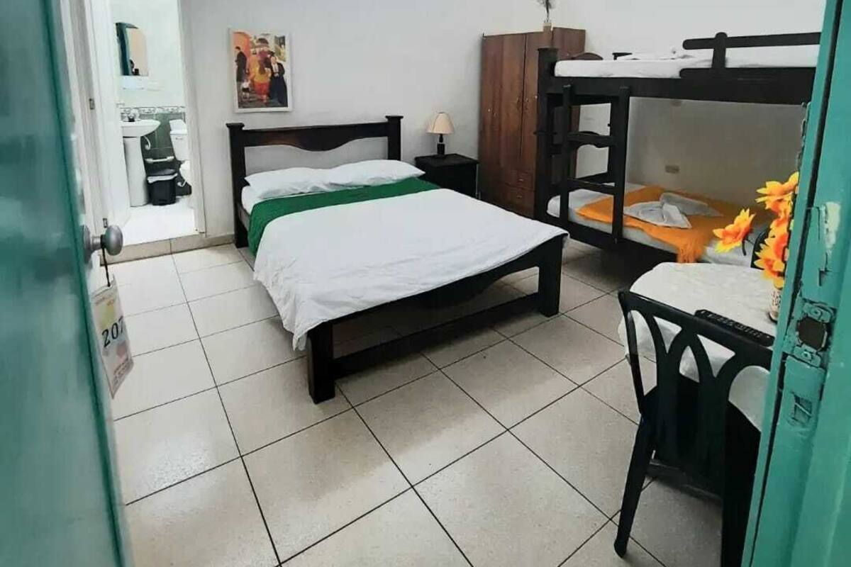 Ein Zimmer mit einem Einzelbett, einem Etagenbett, einem Schreibtisch, einem Stuhl, einem Schrank und einem Fenster.