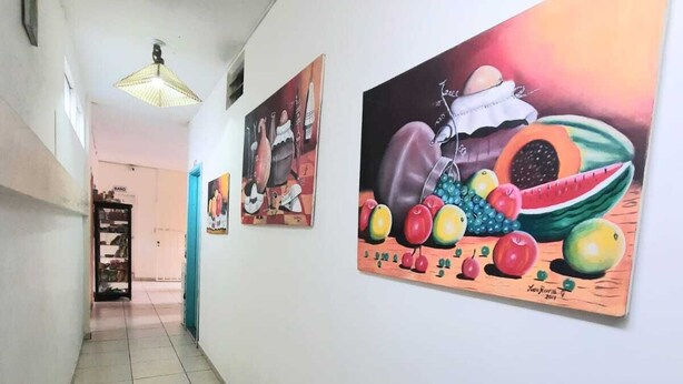 A hallway with tiled flooring and walls adorned with colorful fruit paintings. - san gil tours  (San Gil)