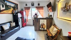 A compact living space with a sofa, a small dining area, and a kitchen area with a refrigerator and a microwave. - san gil tours  (San Gil)